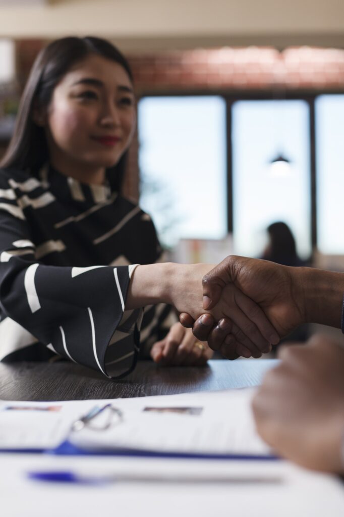 Asian recruiter shaking hands with entrepreneur during interview meeting